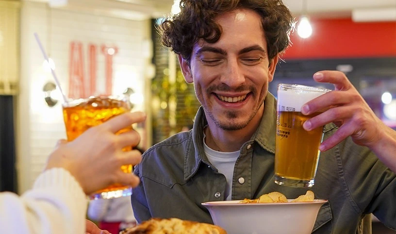 Young man with glass of beer in hand enjoying an Aperitivo in company